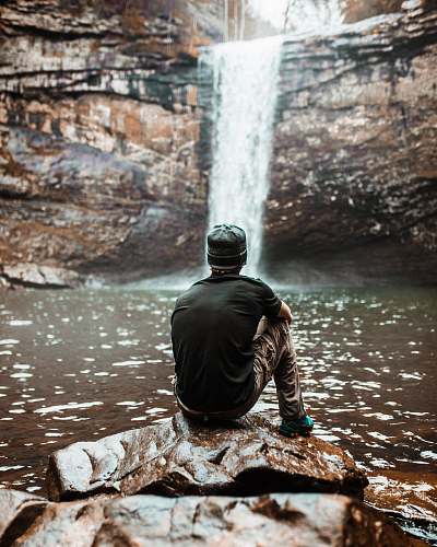 lookout mountain man sitting on brown rock near waterfalls at day time man